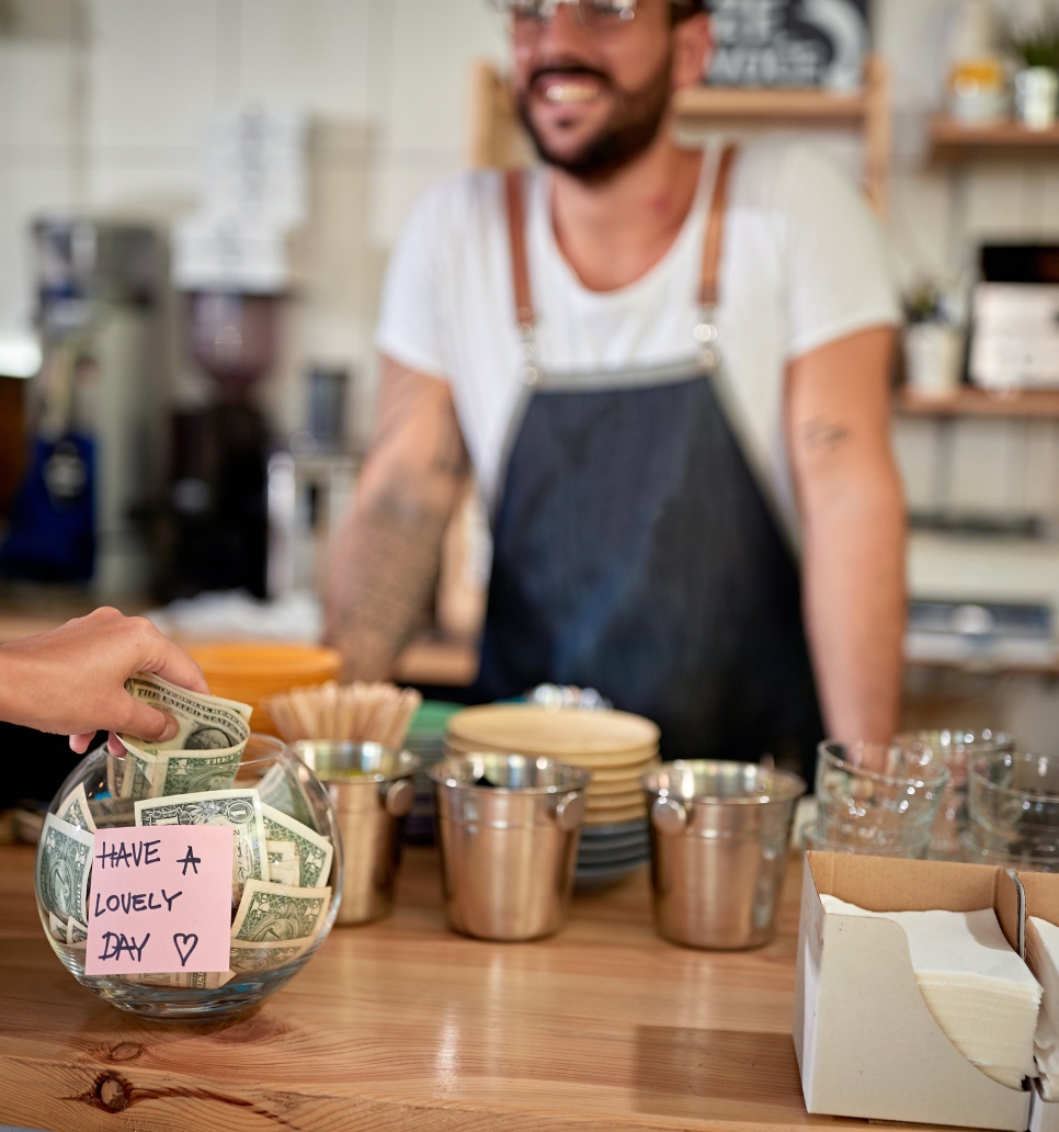Satisfied customer leaving tip in a bowl with a positive message on a sticker